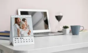 Tischkalender aufgestellt auf Tisch neben Laptop und Weinglas