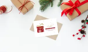 Weiße Weihnachtskarte mit rotem Geschenk und braunem Umschlag zu Weihnachten gestalten