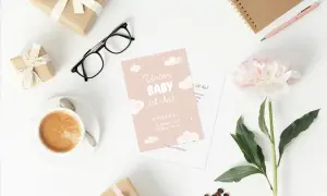 Rosa Babykarte auf weißem Hintergrund mit Accessoires wie schwarzer Brille